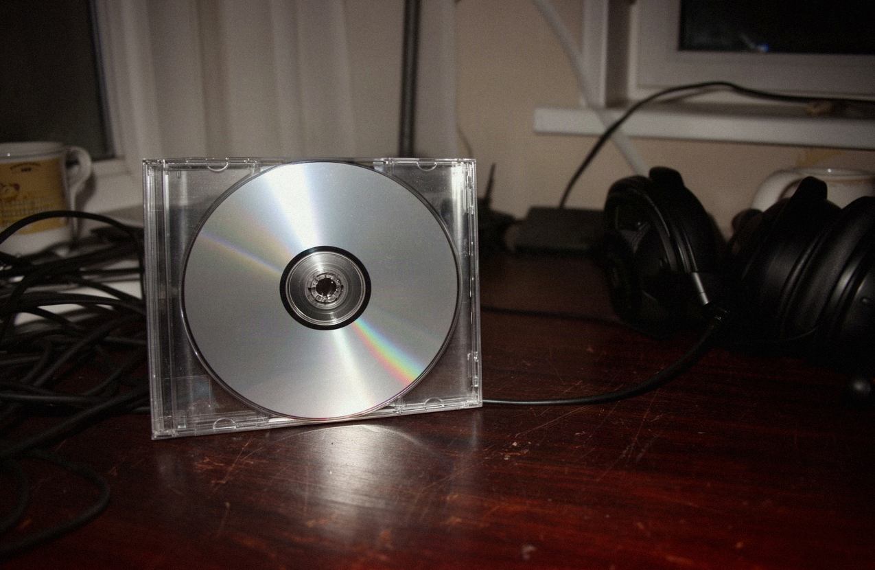 Srebrna płyta CD obok pustego pudełka jewel case na biurku w domowym studiu